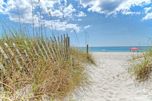 A sandy beach path with wooden posts and grass. - Villa Chateau! Steps to the Beach! (Panama City Beach)