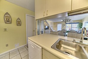 A kitchen with a dishwasher, a double sink, and a staircase leading to another room. - Villa Chateau! Steps to the Beach! (Panama City Beach)