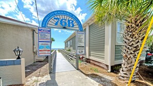 A pathway leading to a beach house with a sign indicating no lifeguard on duty and beach rules. - Villa Chateau! Steps to the Beach! (Panama City Beach)