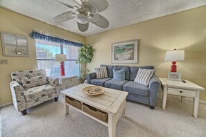 Un salon comprenant un canapé, un fauteuil, une table basse et un ventilateur de plafond.