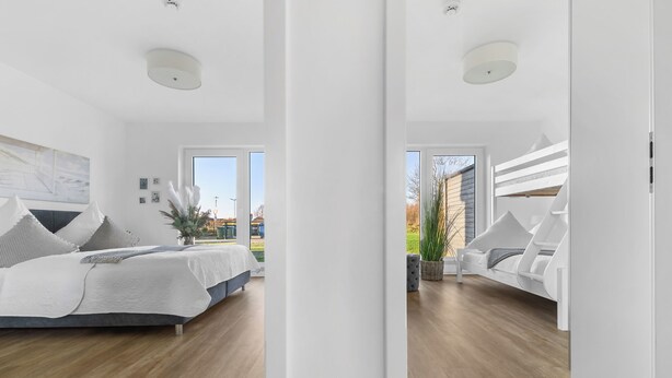 A modern bedroom with a large bed, a bedside table, and a view of the outdoors. - Vacation apartment Küstenhuus in the North Sea resort: A vacation at the North Sea with sauna, (Büsum)