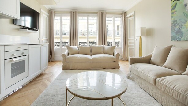 A living room with a sofa, a coffee table, and a TV. - Sublime Apartment Haussmann Opera (Paris)