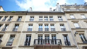 A multi-story building with classical architecture, featuring evenly spaced windows and balconies. - Sublime Apartment Haussmann Opera (Paris)