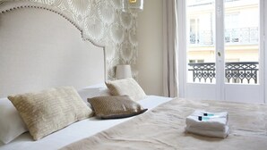 A neatly made bed with pillows, a bedside lamp, and a view of a balcony with a railing. - Sublime Apartment Haussmann Opera (Paris)