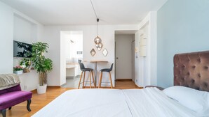 Una habitación de hotel moderna con una cama grande, un área de comedor y una pequeña cocina.