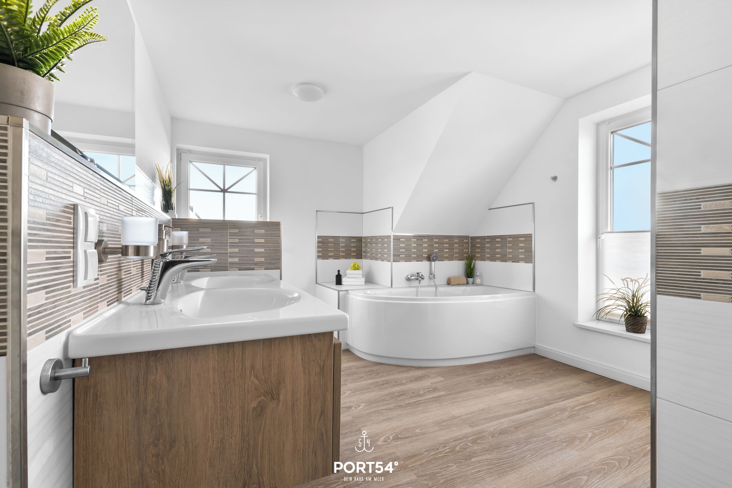 Ein modernes Badezimmer mit einer freistehenden Badewanne, einem großzügigen Waschtisch mit Holdekor und einem Fenster für natürliches Licht.