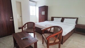 Une chambre à coucher comprenant un lit, deux chaises en bois, une petite table, une armoire et une table de chevet.