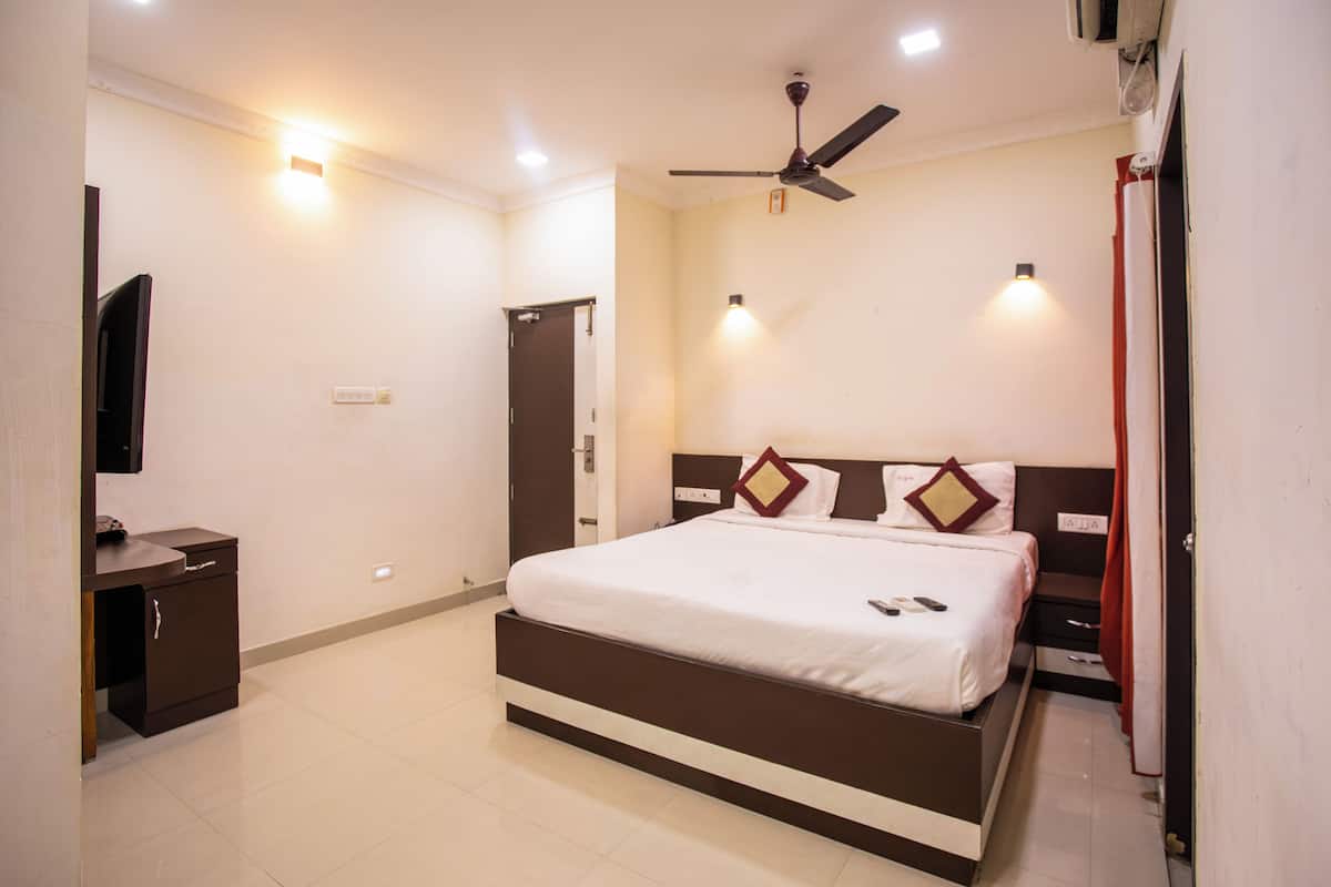 A hotel room with a bed, bedside table, ceiling fan, and wall-mounted light fixtures.
