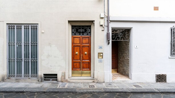 Un edificio con una puerta doble de madera, una reja metálica y un ventanal pequeño.