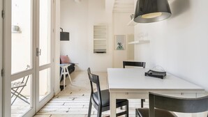 Una cocina moderna con encimera blanca, sillas negras y una lámpara colgante.