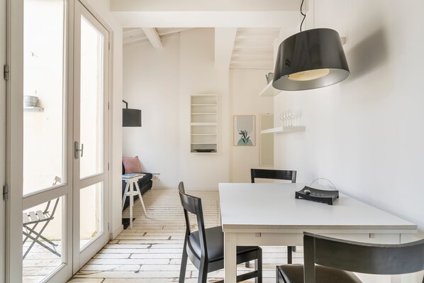 Une cuisine moderne avec un plan de travail blanc, des chaises noires et un luminaire suspendu.