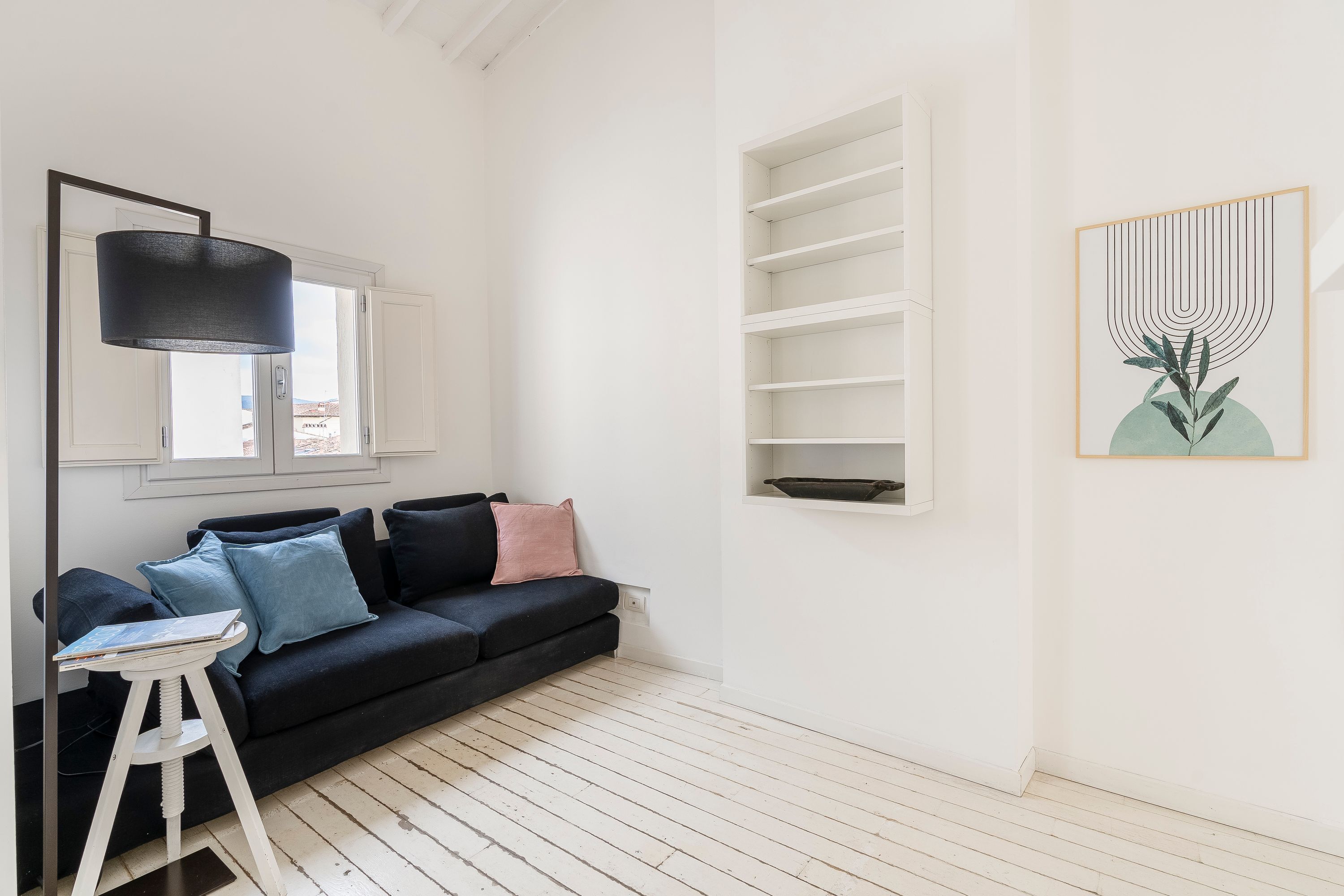 Ein modernes Wohnzimmer mit einem schwarzen Sofa, einem weißen Beistelltisch und einer schwarzen Stehlampe.