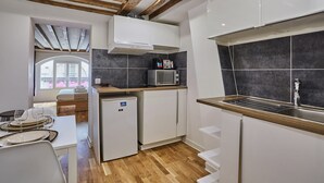 A compact kitchen with modern appliances, a built-in oven, and a window overlooking a balcony. - Charming Apartment Center of Paris (Paris)