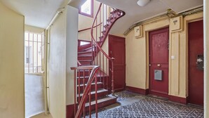 A staircase with red railings leading to a landing with a red door. - Charming Apartment Center of Paris (Paris)