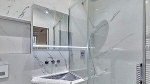 A modern bathroom with a glass-enclosed shower, a marble sink, and a large mirror. - Cosi Apartment Bastille-le Marais (Paris)