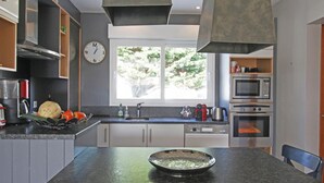 A modern kitchen with a central island, stainless steel appliances, and a large window providing natural light. - Spacious house near the beach, perfect for families, pets allowed (Saint-Germain-sur-Ay)