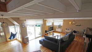 A spacious living area with a dark sofa, a patterned rug, and a dining table. - Spacious house near the beach, perfect for families, pets allowed (Saint-Germain-sur-Ay)