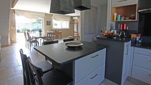 A modern kitchen with a central island, a dining area with chairs, and a view into the living space. - Spacious house near the beach, perfect for families, pets allowed (Saint-Germain-sur-Ay)