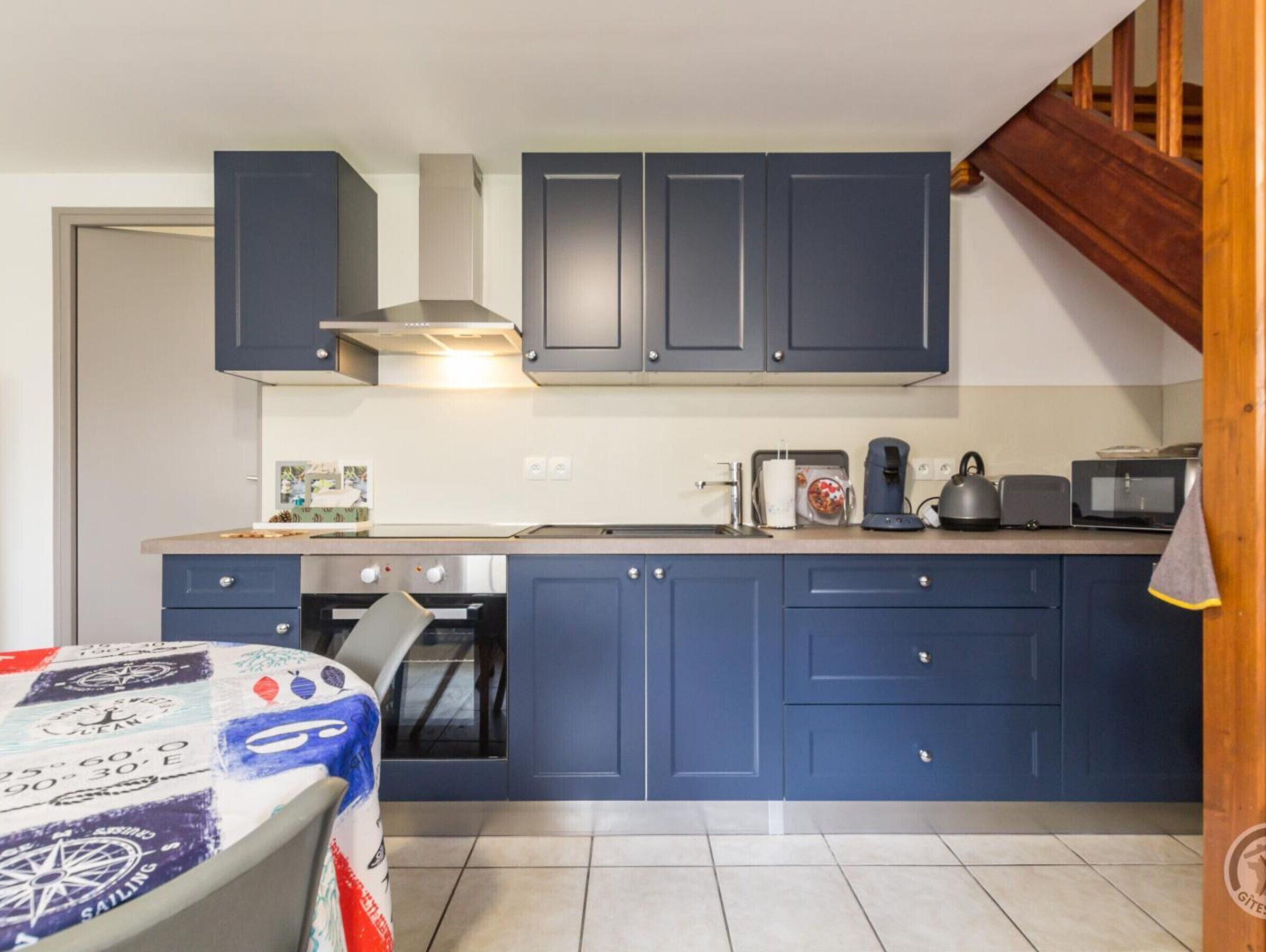 Una cocina compacta con armarios azul oscuro, una estufa y un microondas.