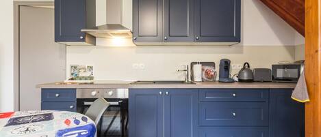 Una cocina compacta con armarios azul oscuro, una estufa y un microondas.