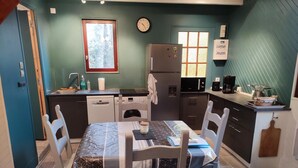 Una cucina compatta con un tavolo da pranzo, sedie, una sveglia e una finestra.