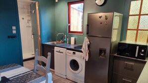 Una cucina compatta con lavatrice, frigorifero, microonde e lavello.