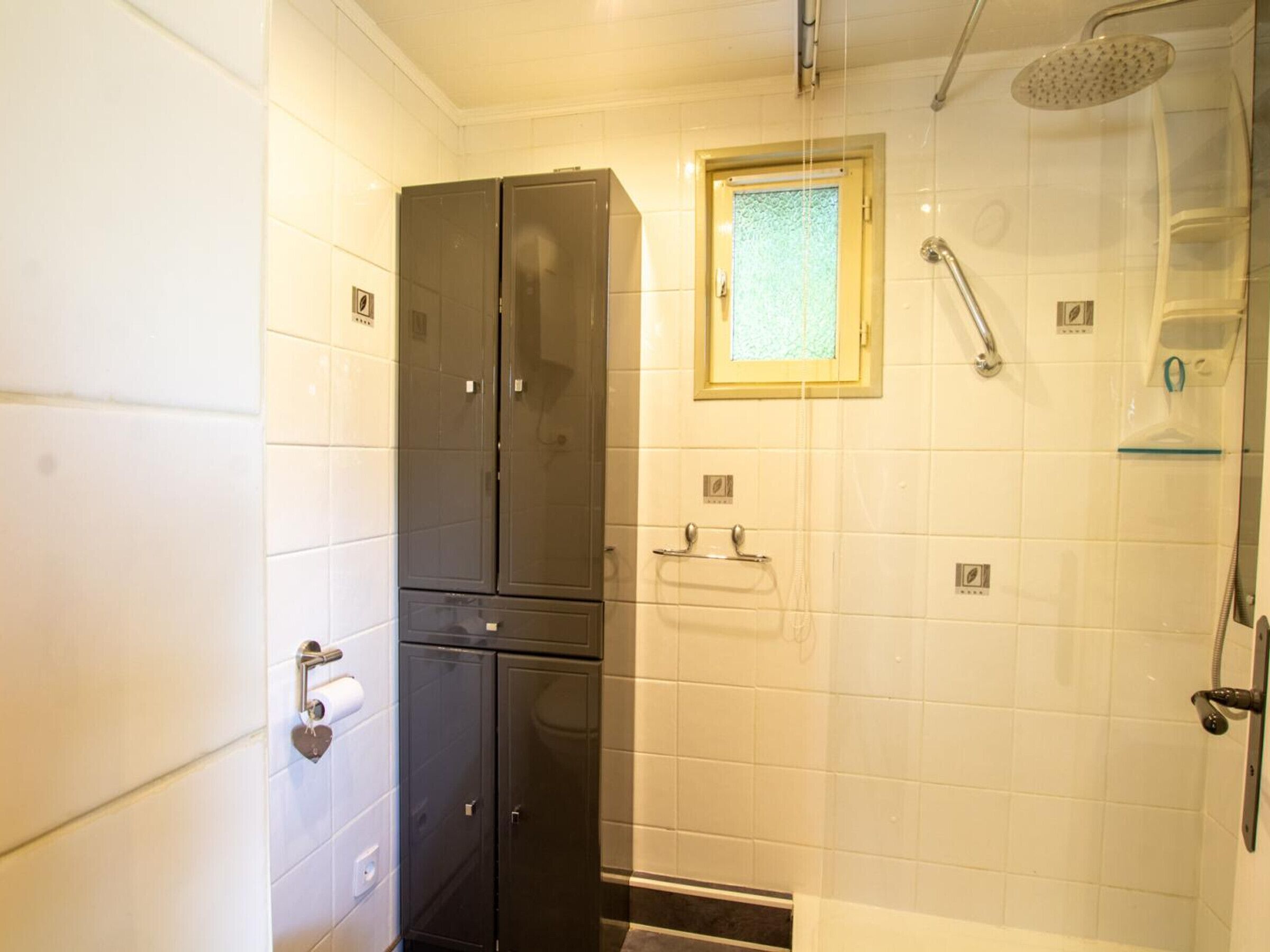 Een badkamer met een douche, toilet en wastafel. Er is een handdoekrek en een glazen douchedeur.