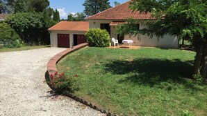 A house with a red-tiled roof, a gravel driveway, and a grassy lawn. - Dordogne Getaway: Riverside House with Private Parking (Mauzac-et-Grand-Castang)