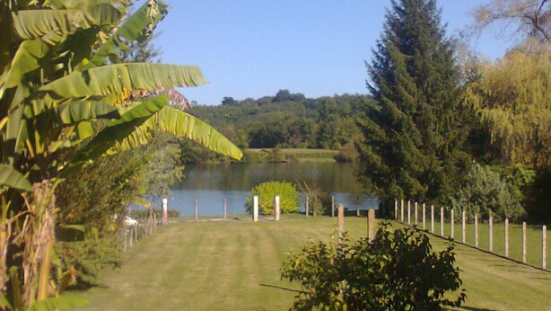 A grassy area with a pond, trees, and a fence. - Dordogne Getaway: Riverside House with Private Parking (Mauzac-et-Grand-Castang)