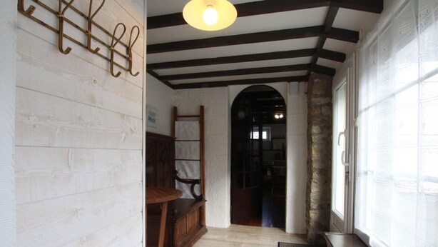 Un pasillo con piso de madera, un banco de madera, una escalera y una ventana con cortinas estampadas.