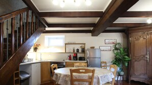 Una cocina acogedora con vigas de madera, una mesa de comedor con sillas, un refrigerador y un lavabo.