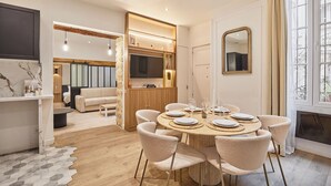 A modern dining area with a round table set for four, surrounded by cushioned chairs. - The Upper Marais Superb Apartment for 8 People (Paris)