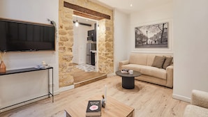 A living room with a TV, a sofa, a coffee table, and a framed picture on the wall. - The Upper Marais Superb Apartment for 8 People (Paris)