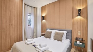 A hotel room with a bed, wooden panel walls, a nightstand, and a wall-mounted lamp. - The Upper Marais Superb Apartment for 8 People (Paris)