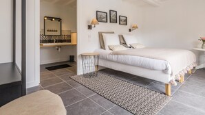 A modern bedroom with a large bed, a bedside table, a mirror, and a wall-mounted lamp. - Spacious house with heated pool and garden, near beaches (Bricqueville-sur-Mer)