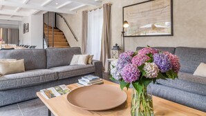 A modern living room with a grey sofa, a wooden coffee table, and a vase of flowers. A staircase is visible in the background. - Spacious house with heated pool and garden, near beaches (Bricqueville-sur-Mer)