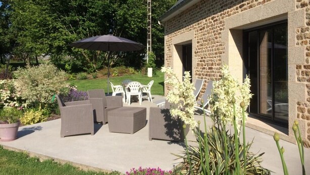 A patio with outdoor furniture, a ladder, and a stone building with a glass door.