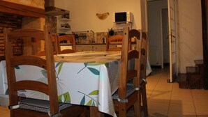 A dining area with a table covered by a leaf-patterned tablecloth, surrounded by wooden chairs.