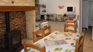 A cozy kitchen with a wood-burning stove, a dining table with chairs, and a microwave above the counter.