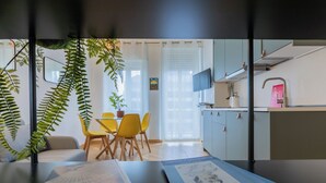 Una cocina moderna con comedor, que incluye una mesa con sillas, una planta en maceta y un televisor montado sobre la encimera.