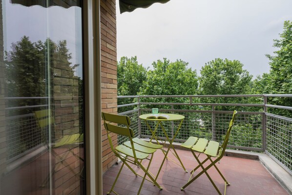 A balcony with a table and chairs, a brick wall, and a view of trees. - Cinema & Bamboo Flats by Wonderful Italy (Turin)
