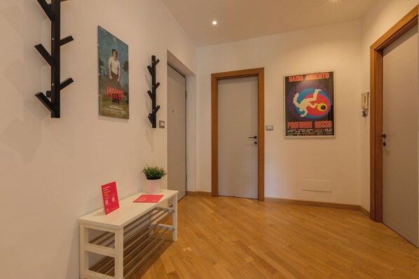 Un couloir avec un plancher en bois, une porte blanche et une affiche accrochée au mur.
