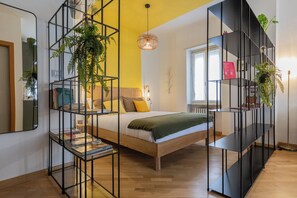 A modern bedroom with a bed, a bookshelf, and a hanging plant. - Cinema & Bamboo Flats by Wonderful Italy (Turin)