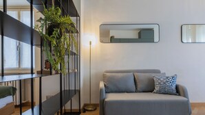 Una sala moderna con un sofá gris, una mesita auxiliar y una planta en maceta.