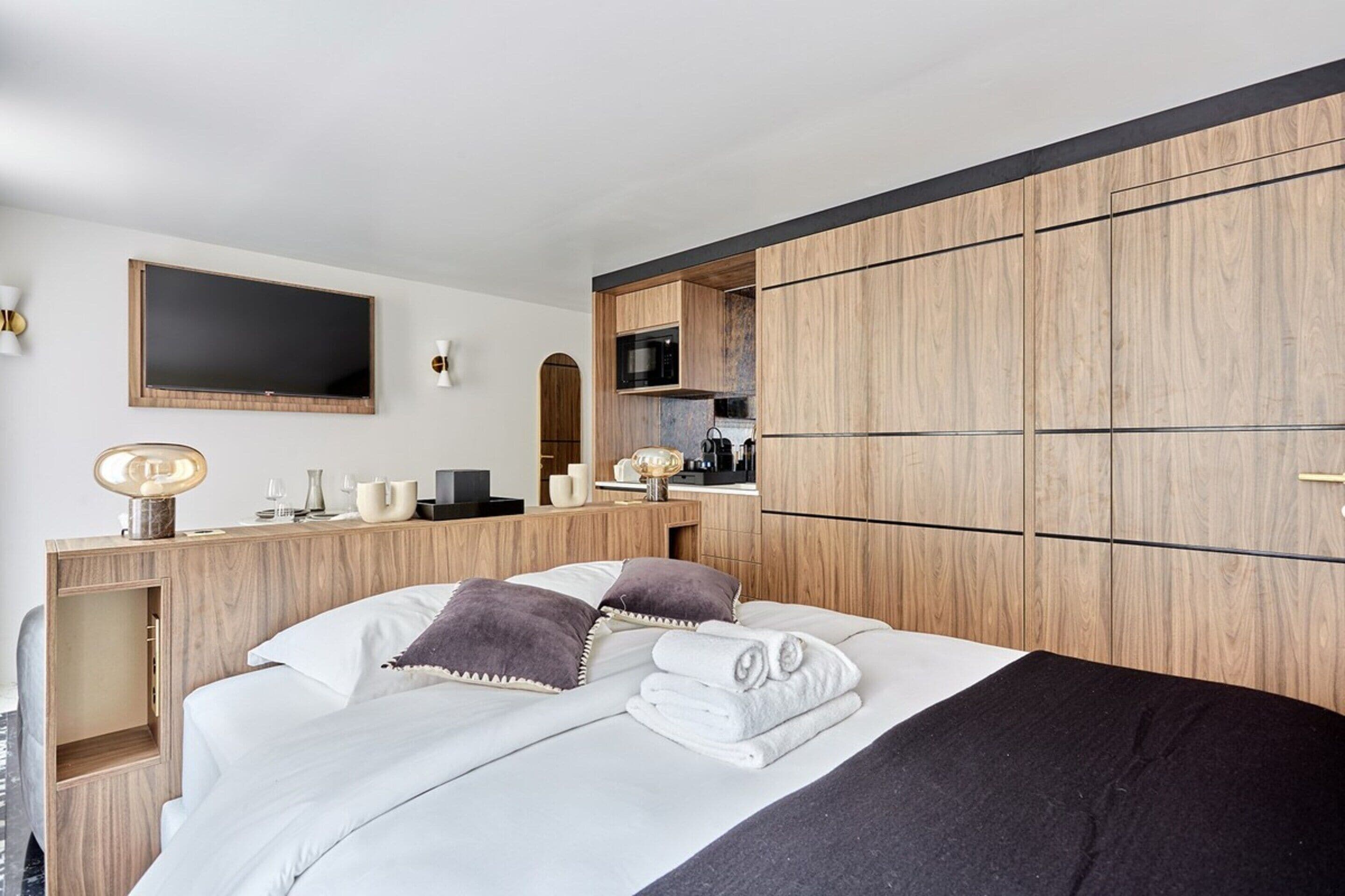 Una habitación de hotel moderna con cama, escritorio con televisor de pantalla plana, microondas y armario.