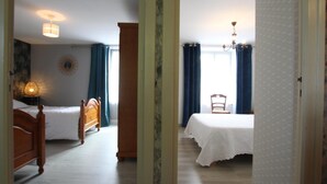 Una habitación con dos camas, cabecero de madera, candelabro y ventana con cortinas.