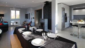 A modern kitchen with a built-in oven and a dining area set for six with a long table. - House in Gratot, near beaches, WIFI, parking (Gratot)