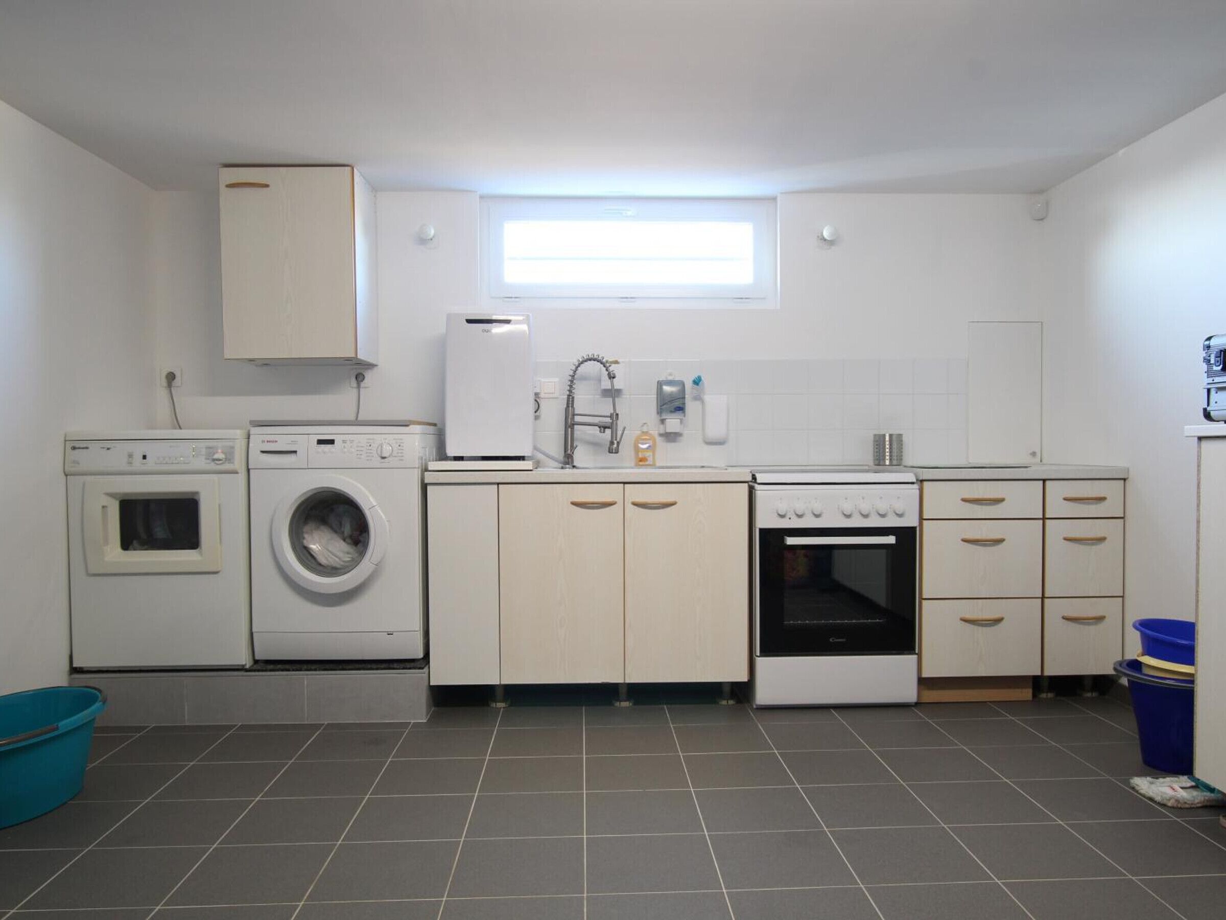 A compact kitchen with a washing machine, a small oven, and a sink.