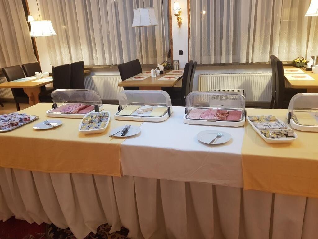 A dining area with tables set for a meal, featuring covered food containers and plates.