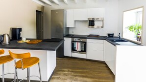 Una cocina moderna con armarios blancos, electrodomésticos de acero inoxidable y suelo de madera.